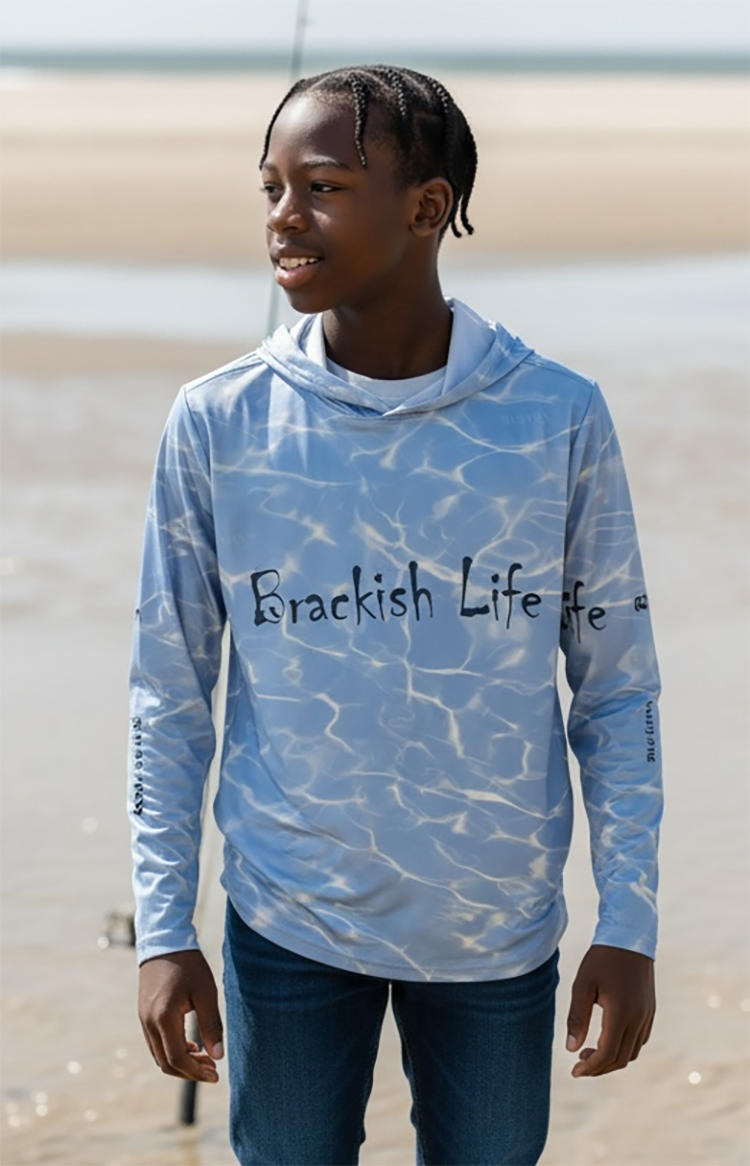 Person wearing a blue tie-dye hoodie with 'Brackish Life' text on a beach.